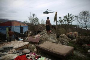 A man watches an army helicopter flying over his damaged home in Cajobabo after the passage of Hurricane Matthew. REUTERS/Alexandre Meneghini